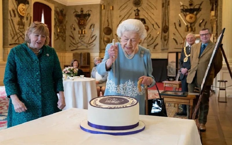 Ratu Elizabeth memotong kue khusus untuk perayaan sebelum Accession Day/Joe Giddens-Getty Images.