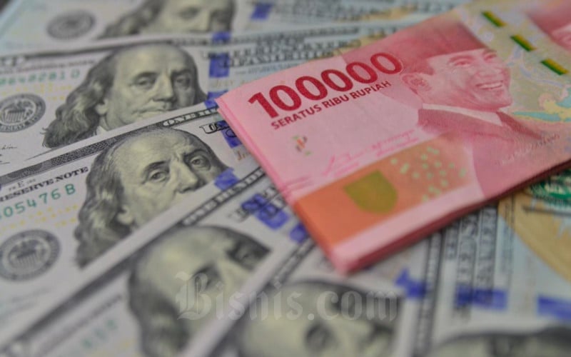 Petugas menunjukkan mata uang dolar AS dan rupiah di Money Changer, Jakarta, Senin (19/4/2021). Bisnis/Fanny Kusumawardhani