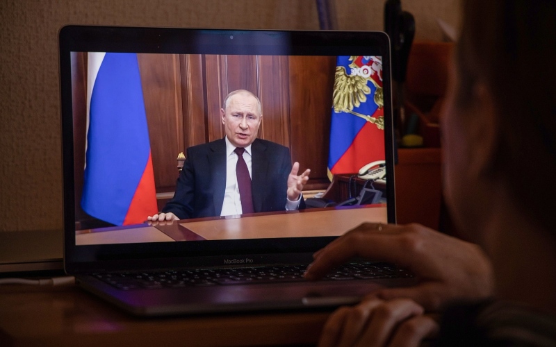 Seorang warga menonton siaran langsung Vladimir Putin, Presiden Rusia, saat menyampaikan pidato, di Moskwa, Rusia, Senin (22/2/2022). /Bloomberg-Andrey Rudakov