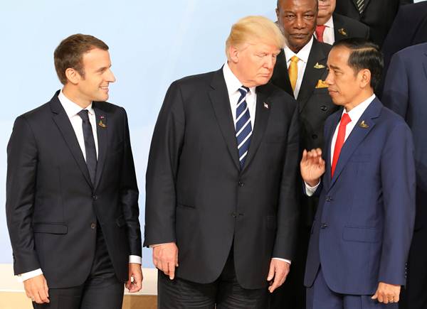 Presiden Joko Widodo (kanan) berbincang dengan Presiden Amerika Serikat Donald Trump (tengah), disaksikan Presiden Prancis Emmanuel Macron (kiri) di sela-sela sesi foto bersama pada hari pertama Konferensi Tingkat Tinggi (KTT) G20, di Hamburg, Jerman, Jumat (7/7). REUTERS/Ludovic Marin