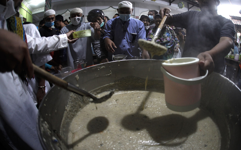 Petugas membagikan takjil Bubur Samin Banjar kepada warga di halaman Masjid Darussalam, Solo, Jawa Tengah, Minggu (3/4/2022). Tradisi membagikan Bubur Samin secara gratis setiap jelang buka puasa tersebut dimulai oleh komunitas warga keturunan Banjarmasin di Solo sejak tahun 1985 dan menyediakan 1.300 porsi per harinya./Antara-Maulana Surya.