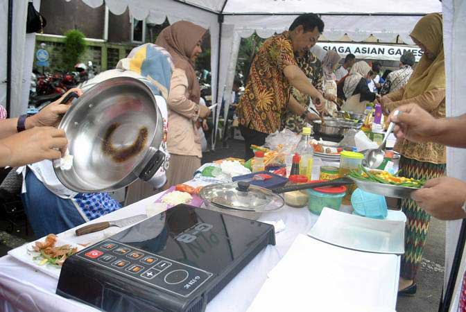 Sejumlah peserta memasak menggunakan kompor induksi di halaman kantor PLN UP3 Kota Bogor, Jawa Barat, Jumat (15/2/2019)./ANTARA-Arif Firmansyah