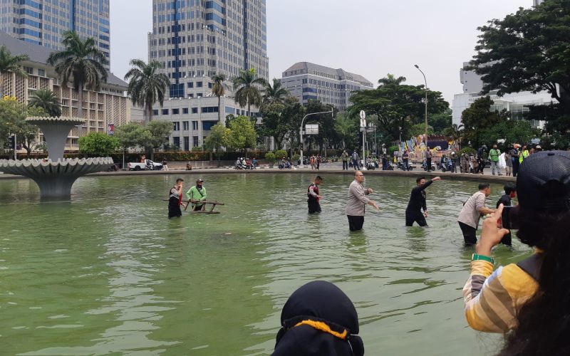 Aparat kepolisian mengamankan seorang pemuda yang mencoba memanjat air mancur di kawasan Patung Kuda, Jakarta. Aksi itu dilakukan menjelang demo mahasiswa yang tergabung dalam BEM SI, Senin 11 April 2022 / Bisnis-Pernita Hestin Untari