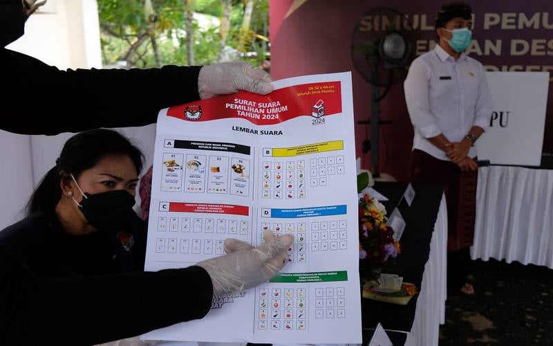 Anggota KPPS menunjukkan surat suara kepada pemilih saat simulasi pemungutan dan penghitungan suara dengan desain surat suara dan formulir yang disederhanakan dalam persiapan penyelenggaraan Pemilu serentak tahun 2024 di Kantor KPU Provinsi Bali, Denpasar, Bali, Kamis (2/12/2021). /Bisnis
