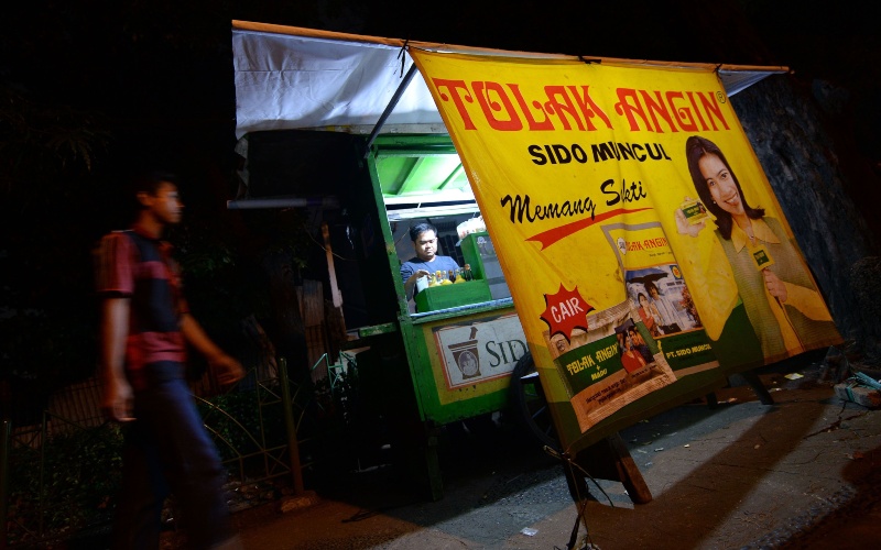 Sebuah iklan Tolak Angin produksi PT Industri Jamu Dan Farmasi Sido Muncul Tbk. (SIDO) terpampang di sebuah warung pinggir jalan di Jakarta, Minggu (16/2/2014). Bloomberg/Dimas Ardian
