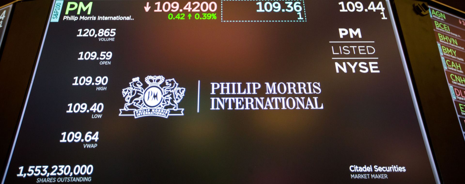 Sebuah monitor menampilkan papan nama Philip Morris International Inc. di lantai New York Stock Exchange (NYSE) di New York. /Bloomberg