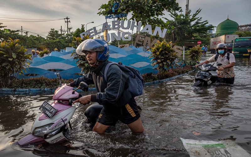 Sejumlah pekerja mendorong motornya yang mogok untuk menerobos banjir limpasan air laut ke daratan atau rob yang merendam kawasan Pelabuhan Tanjung Emas Semarang, Jawa Tengah, Senin (23/5/2022)./Antara-Aji Styawan.