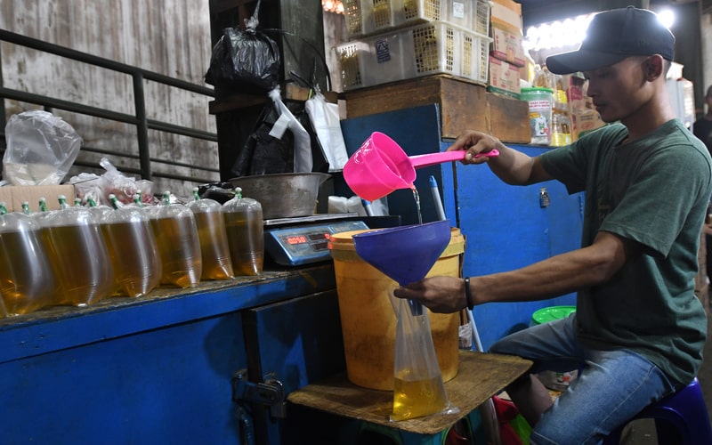 Pedagang memasukkan minyak goreng curah ke dalam kantong plastik di Pasar Senen, Jakarta, Selasa (31/5/2022). Kementerian Perindustrian mencabut subsidi minyak goreng curah kepada pelaku usaha mulai Selasa (31/5/2022) menyusul dikeluarkannya Permendag Nomor 30 Tahun 2022 yang mengatur ketentuan ekspor CPO dan turunan lainnya dan Permendag Nomor 33 Tahun 2022 tentang Tata Kelola Minyak Goreng Curah Sistem DMO-DPO./Antara-Aditya Pradana Putra.