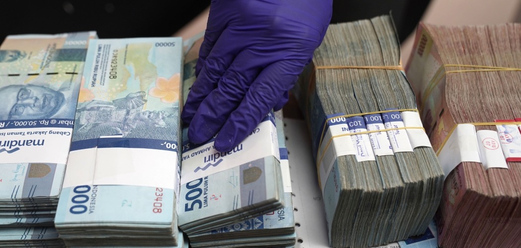 Pegawai money changer merapikan uang nominal Rp50.000 dan Rp100.000 di Jakarta, Indonesia, Selasa (18/8/2020)./Bloomberg-Dimas Ardian