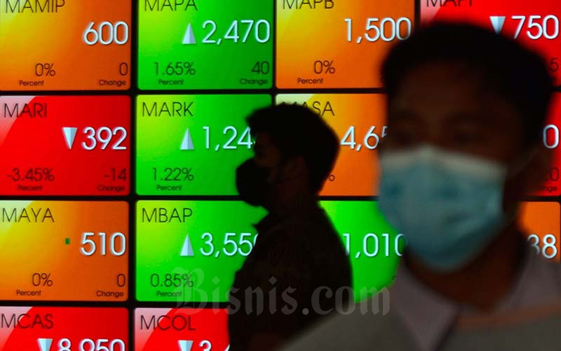 Karyawan melintas di dekat layar pergerakan indeks harga saham gabungan (IHSG) di Bursa Efek Indonesia (BEI) Jakarta, Rabu (19/1/2022). Bisnis/Fanny Kusumawardhani
