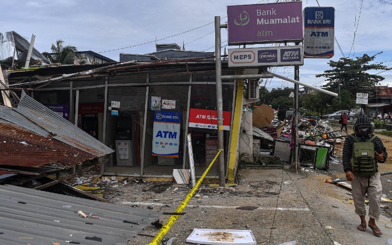 Warga melintas di dekat anjungan tunai mandiri yang rusak akibat gempa bumi magnitudo 6,2 di Mamuju, Sulawesi Barat, Sabtu (16/1/2021). Badan Nasional Penanggulangan Bencana (BNPB) menyatakan korban meninggal dunia akibat gempa di Sulawesi Barat per Sabtu 16 Januari sore sebanyak 46 orang. /ANTARA