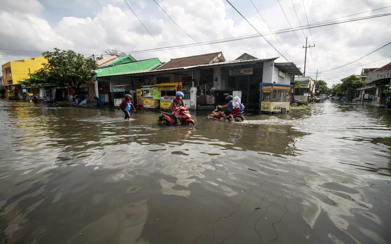 Warga mendorong kendaraannya yang mogok saat mencoba menerobos banjir di perumahan kawasan Tropodo, Waru, Sidoarjo, Jawa Timur, Senin (13/6/2022). Curah hujan tinggi dan buruknya drainase mengakibatkan ratusan rumah dikawasan tersebut terendam banjir./Antara-Umarul Faruq.