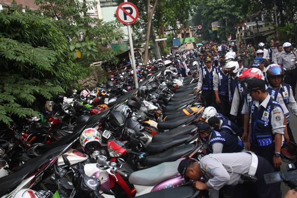 Petugas Dinas Perhubungan DKI Jakarta, mengembosi motor yang nekat parkir liar di Jalan Kebon Kacang, Tanah Abang, Jakarta Pusat, Jumat (12/6)./Antara