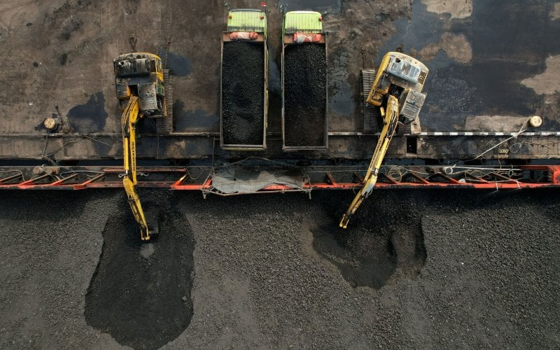 Batu bara di atas tongkang dimuat ke truk di Pelabuhan Cirebon, Jawa Barat, Rabu, (11/5/2022). Harga batu bara yang terus memanas terus menekan ongkos produksi semen, yang menggerus kinerja penjualan dalam negeri dan ekspor. Bloomberg - Dimas Ardian