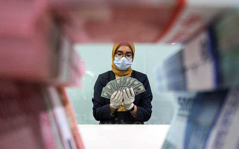 Ilustrasi - Karyawati salah satu bank memperlihatkan uang rupiah dan dolar di Jakarta, Kamis (29/4/2021). Bisnis/Arief Hermawan P
