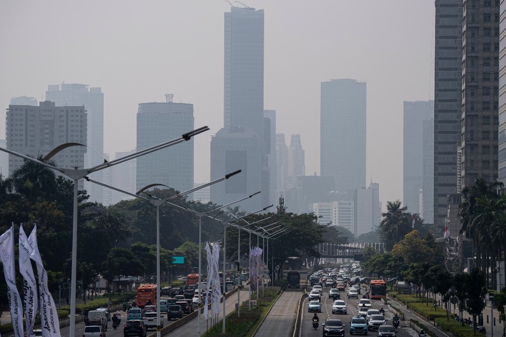 Kendaraan melintas dengan latar belakang gedung bertingkat yang terlihat berkabut di Jalan Jenderal Sudirman, Jakarta, Rabu (22/6/2022). /Antara Foto-Sigid Kurniawan-hp.