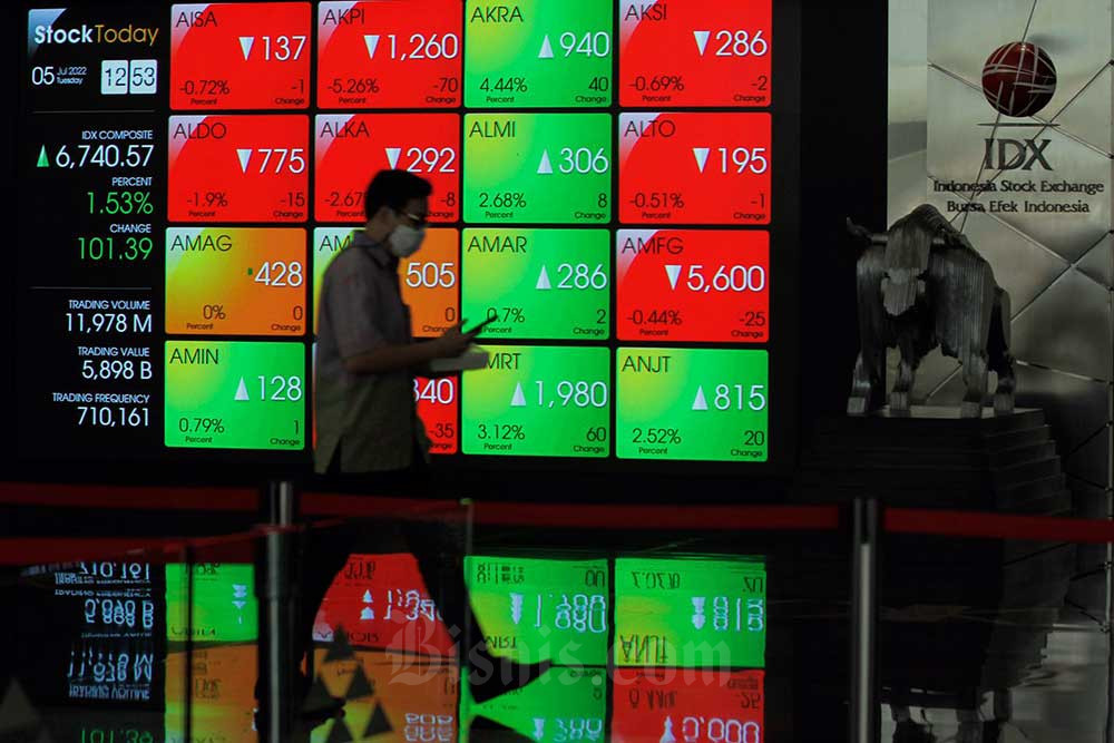 Karyawan melintas di depan layar pergerakan indeks harga saham gabungan (IHSG) di Bursa Efek Indonesia (BEI), Jakarta, Selasa (5/7/2022). Bisnis/Fanny Kusumawardhani 