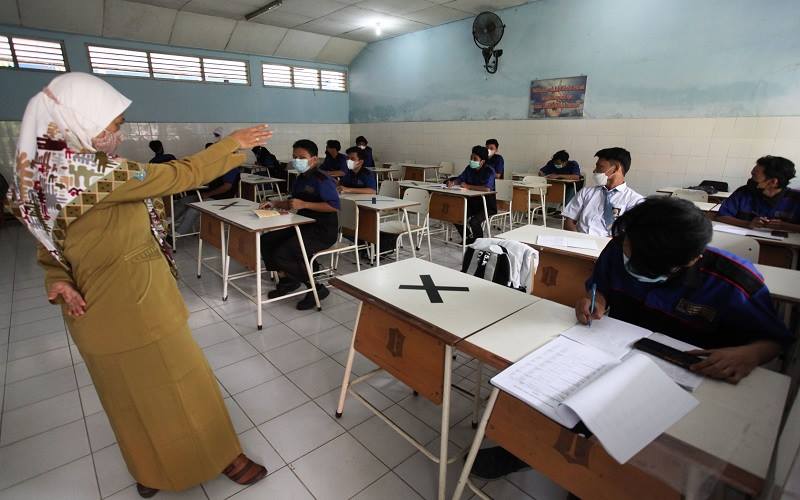 Guru mengajar muridnya di ruang kelas di SMK Negeri 7 Surabaya, Jawa Timur, Senin (30/8/2021). Pemprov Jawa Timur memulai pembelajaran tatap muka (PTM) secara terbatas di 2.536 SMA/SMK dan SLB di 20 kabupaten/kota di Jawa Timur yang telah menerapkan PPKM Level 2 dan 3, sedangkan di wilayah PPKM level 4 kegiatan PTM secara terbatas belum digelar. ANTARA FOTO/Didik Suhartono