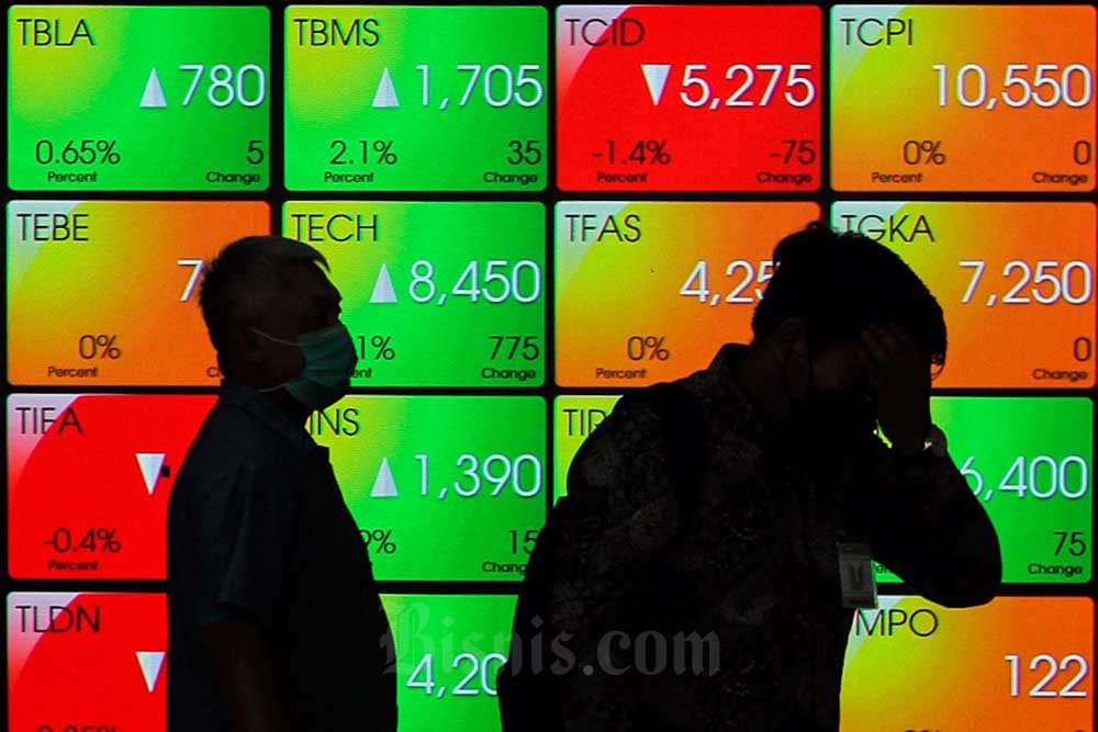 Karyawan melintas di dekat layar pergerakan indeks harga saham gabungan (IHSG) di Bursa Efek Indonesia, Jakarta, Rabu (20/7/2022). Bisnis/Fanny Kusumawardhani