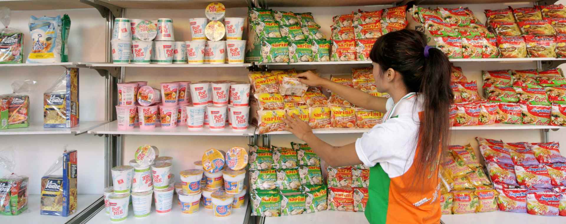 Seorang pekerja mengisi rak dengan produk makanan PT Indofood Sukses Makmur di Jakarta Fair, Kamis, (26/6/2008). Bloomberg - Dimas Ardian