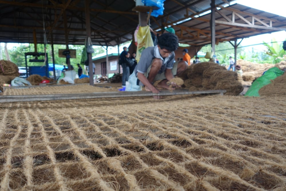 Pekerja menganyam tali serabut kelapa menjadi cocomesh atau coconet di Desa Geli toli, Kecamatan Maba, Kabupaten Halmahera Timur, Maluku Utara, Selasa (16/8/2022). Cocomesh yang juga disebut jaring serabut kelapa digunakan untuk reklamasi lahan bekas tambang/Bisnis-Akhirul Anwar   
