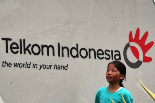 Pejalan kaki berjalan melewati logo Telkom di Jakarta, Senin (27/11)./JIBI-Dedi Gunawan