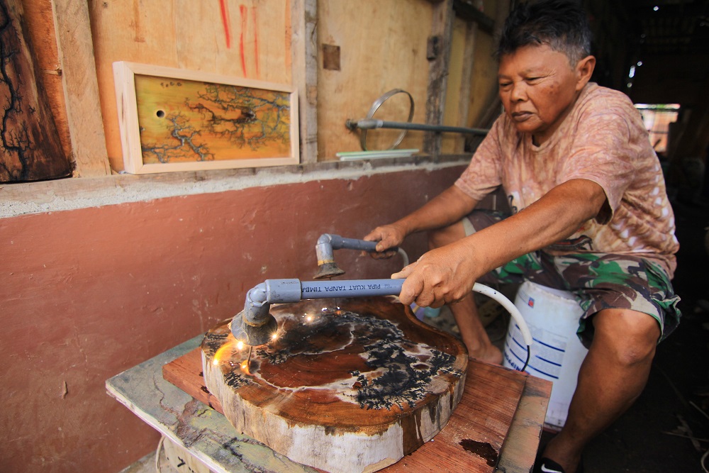 Jarot tengah melukis di atas potong kayu dengan cara menggunakan aliran listrik bertegangan 2.200 watt, di Parak Laweh, Kota Padang, Sumatra Barat, Kamis (1/9/2022). /Bisnis-Noli Hendra
