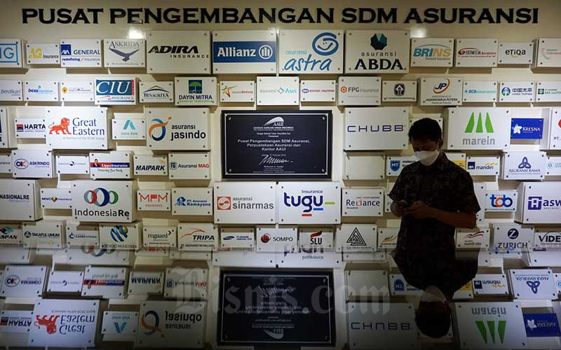 Karyawan beraktivitas di dekat logo-logo perusahaan asuransi di kantor Asosiasi Asuransi Umum Indonesia (AAUI) di Jakarta, Rabu (5/1/2021). Bisnis/Suselo Jati