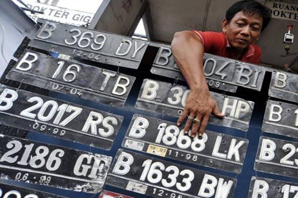 Seorang tukang plat nomor polisi (nopol) merapikan deretan plat nomor registrasi kendaraan bermotor, di kawasan Jatinegara, Jakarta Timur/Antara