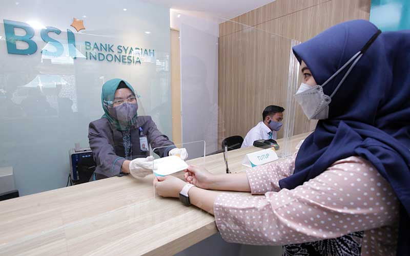 Karyawan melanyani nasabahyang melakukan transaksi di PT Bank Syariah Indonesia KC Jakarta Barat, Kebon Jeruk, Jakarta, Senin (1/2/2021). Bisnis
