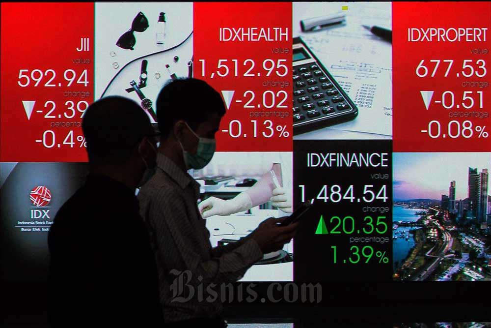 Karyawan melintas di dekat layar pergerakan indeks harga saham gabungan (IHSG) di Bursa Efek Indonesia (BEI), Jakarta, Selasa (26/7/2022). Bisnis/Fanny Kusumawardhani