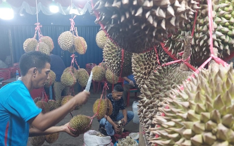Penjual durian di Pasar Kuto Palembang memilih buah kepada pelanggan./Bisnis.com-Abdurachman