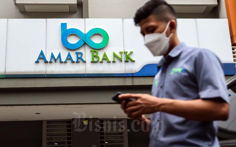 Warga beraktivitas dengan latar logo PT Bank Amar Indonesia Tbk. (AMAR) di Jakarta, Selasa (25/1/2022). Bisnis/Eusebio Chrysnamurti