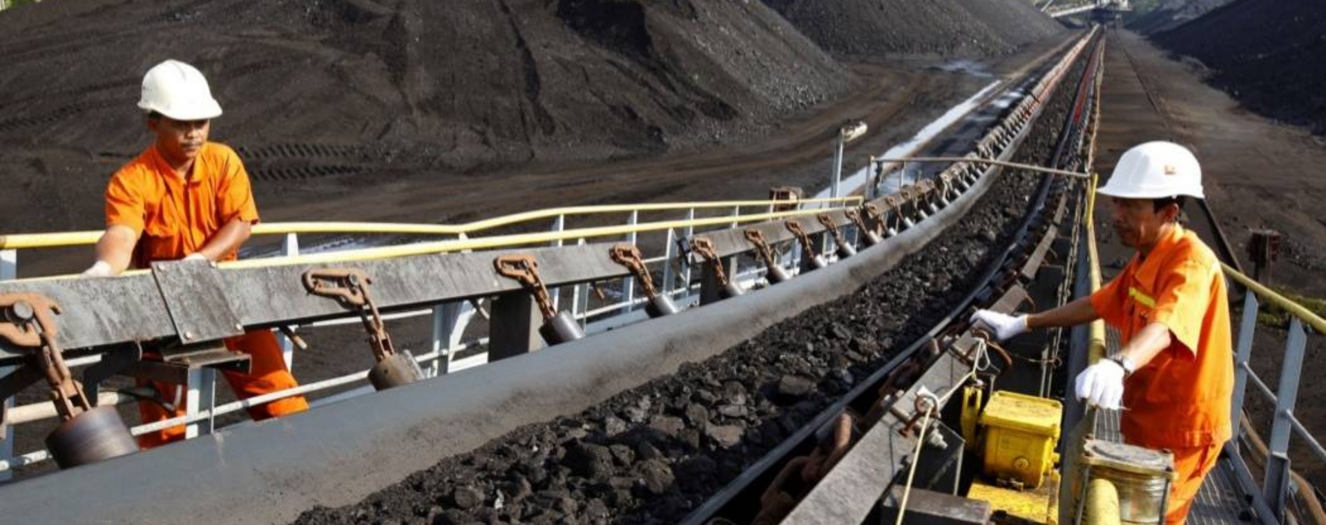 Pekerja melakukan inspeksi pengangkutan batu bara di atas ban berjalan./Bloomberg - Dadang Tri