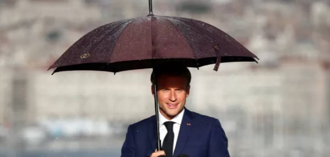 Presiden Prancis Emmanuel Macron memakai payung saat ia memberikan pidato di Palais du Pharo di Marseille, Prancis, Kamis (2/9/2021)./Antara-Reuters.