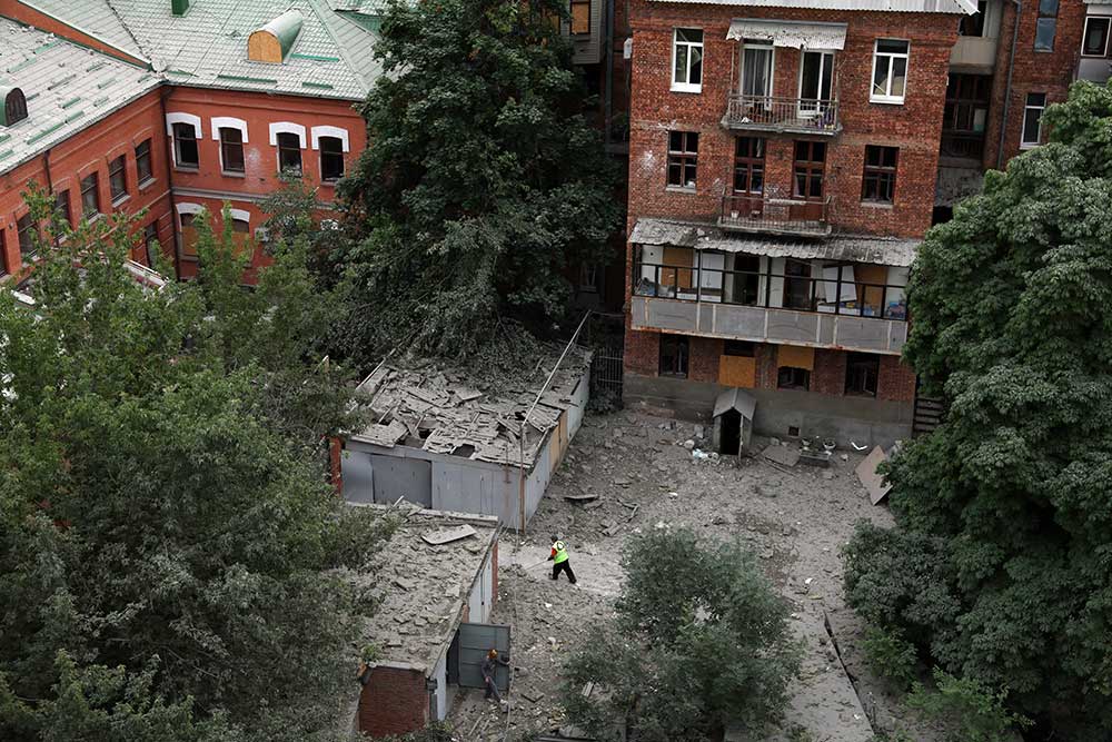 Warga membersihkan puing-puing di sebelah gedung perkantoran yang ditembaki malam sebelumnya di dekat pusat kota Kharkiv saat serangan Rusia ke Ukraina di Kharkiv, Ukraina. REUTERS/Leah Millis