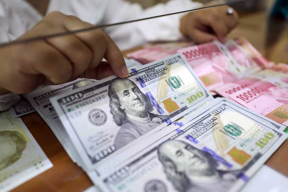 Pegawai menunjukan mata uang rupiah dan dolar Amerika Serikat di Dolar Asia Money Changer, Jakarta, Senin (18/7/2022). Bisnis/Himawan L Nugraha