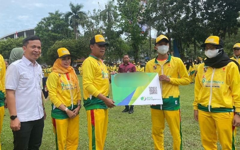Penjabat Wali Kota Pekanbaru Muflihun (tengah) didampingi Kepala BPJamsostek Pekanbaru Panam, Anwar Hidayat (kiri) menyerahkan kartu kepesertaan secara simbolis kepada peserta utusan Pekanbaru di ajang Porprov X Riau 2022. /Istimewa