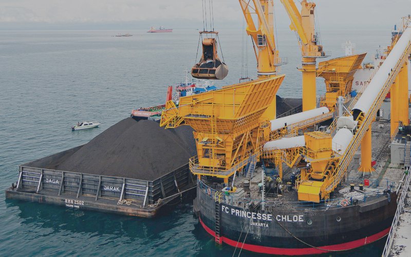 Aktivitas pemindahan muatan batu bara dari tongkang ke kapal induk dengan floating crane./indikaenergy.co.id