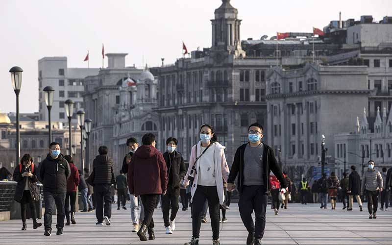 Orang-orang menggunakan masker saat berkumpul di Bund di Shanghai, China, Sabtu (14/3/2020). Bloomberg/Qilai Shen