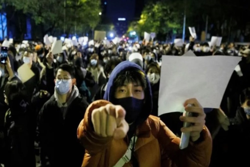 Orang-orang memegang lembaran kertas putih sebagai protes atas pembatasan Covid-19, setelah berjaga bagi para korban kebakaran di Urumqi, di Beijing, China, 27 November 2022./Antara