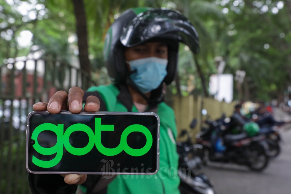 Pengemudi ojek online (ojol) menunjukan logo GoTo di Jakarta, Rabu (26/10/2022). Bisnis/Himawan L Nugraha