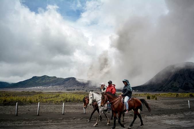 Tiga orang menunggang kuda dengan latar belakang Gunung Bromo./Antara-Umarul Faruq 