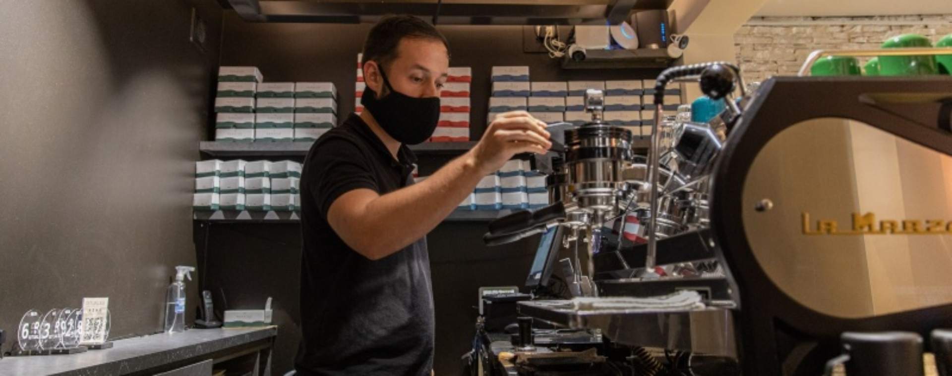 Seorang barista yang mengenakan masker pelindung menggunakan mesin espresso di Rituales Cafe di Medellin, Kolombia, Senin (22/2/2021). Bloomberg/Juan Cristobal Cobo