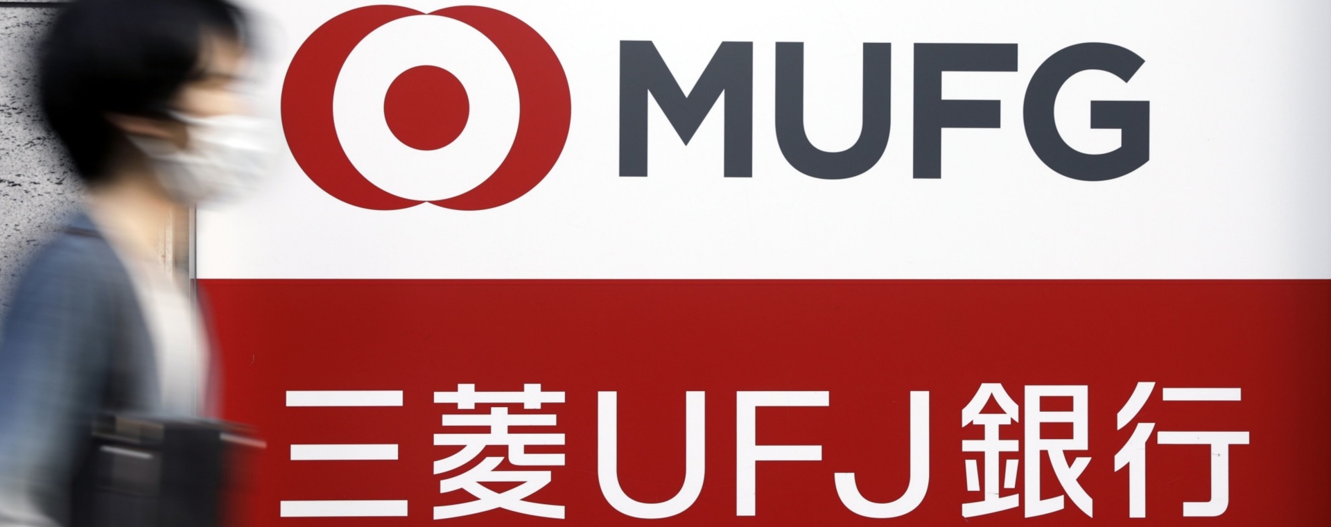 Seorang pejalan kaki berjalan melewati papan nama MUFG Bank Ltd., unit dari Mitsubishi UFJ Financial Group Inc. (MUFG), di luar cabang di Tokyo, Jepang, Rabu, (13/5/2020). Bloomberg - Kiyoshi Ota. 
