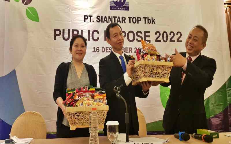 Direktur Utama STTP, Armin (tengah) dan Direktur STTP Suwanto (kanan) memamerkan sejumlah produk makanan ringan saat paparan publik Siantar Top di Surabaya, Jumat (16/12/2022). /Bisnis-Peni Widarti