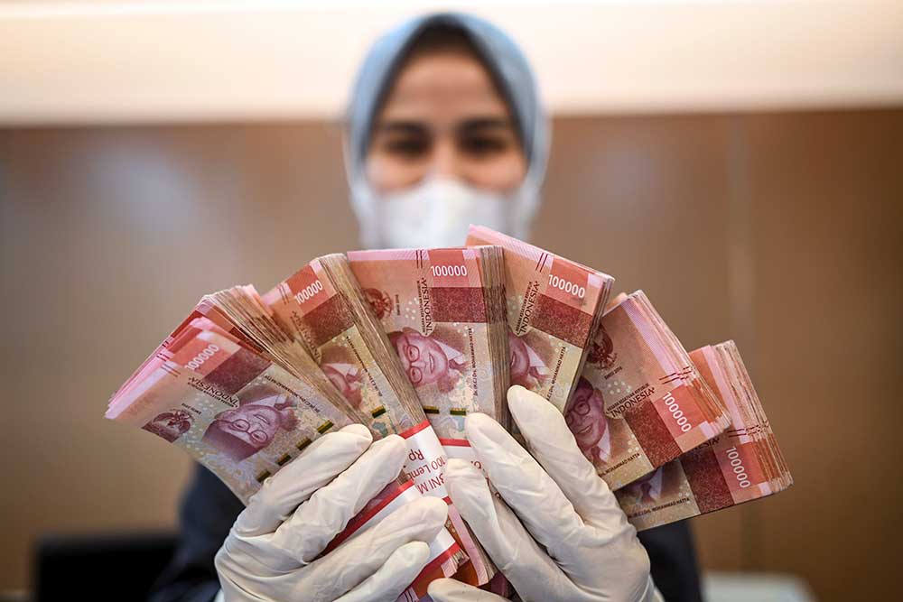 Petugas bank menunjukkan uang di BNI KC Mega Kuningan, Jakarta, Selasa (28/6/2022). ANTARA FOTO/Aprillio Akbar