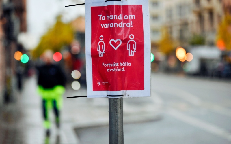 Poster yang meminta warga untuk saling menjaga kesehatan dan menjaga jarak dengan orang lain dipasang di tiang lampu di Stockholm, Swedia, Rabu (11/11/2020)./Bloomberg-Mikael Sjoberg