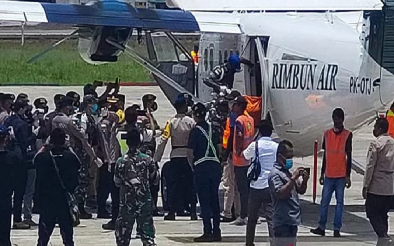 Petugas menurunkan kantong jenazah korban pembantaian oleh KKB dari pesawat Rimbun Air PK-OTJ untuk dibawa ke mobil ambulans di Bandara Mozes Kilangin Timika, Senin (7/3/2022).