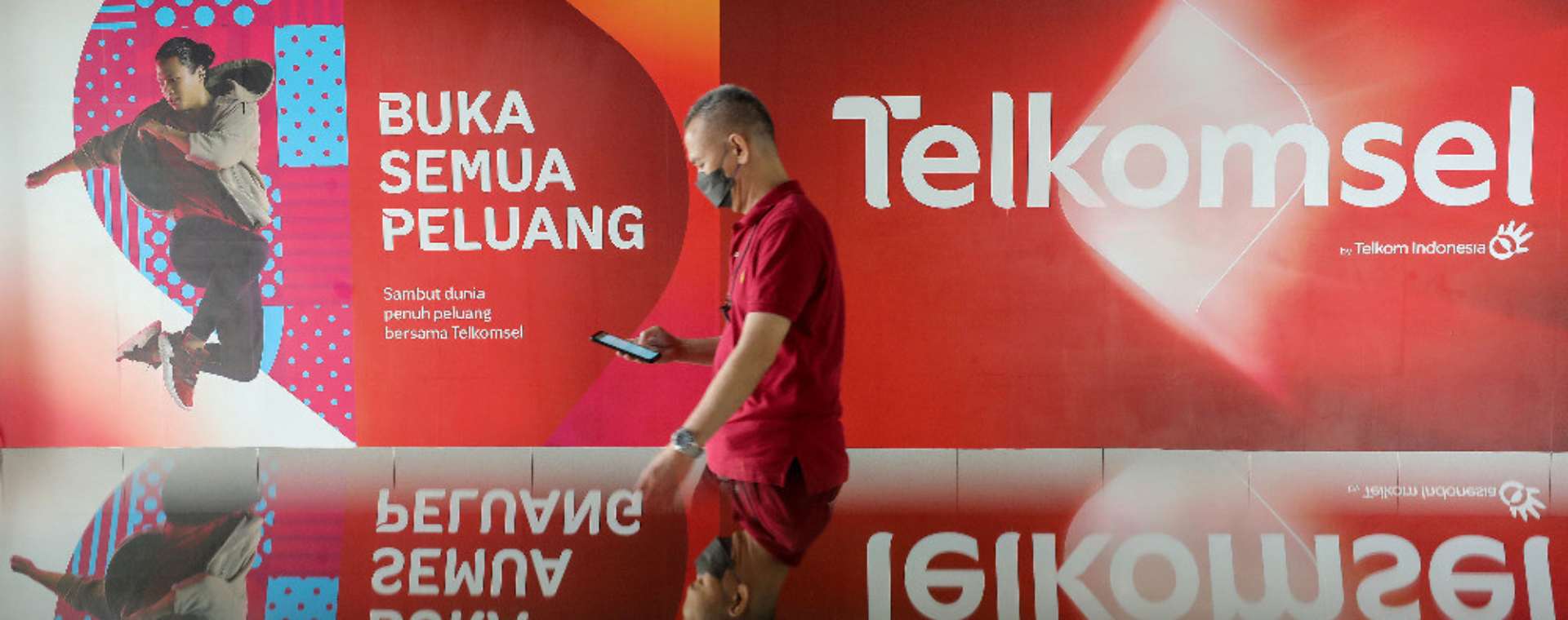 Warga melintasi iklan Telkomsel di Jakarta, Selasa (11/10/2022). Bisnis/Eusebio Chrysnamurti. Suntikan Kekuatan untuk Entitas TLKM